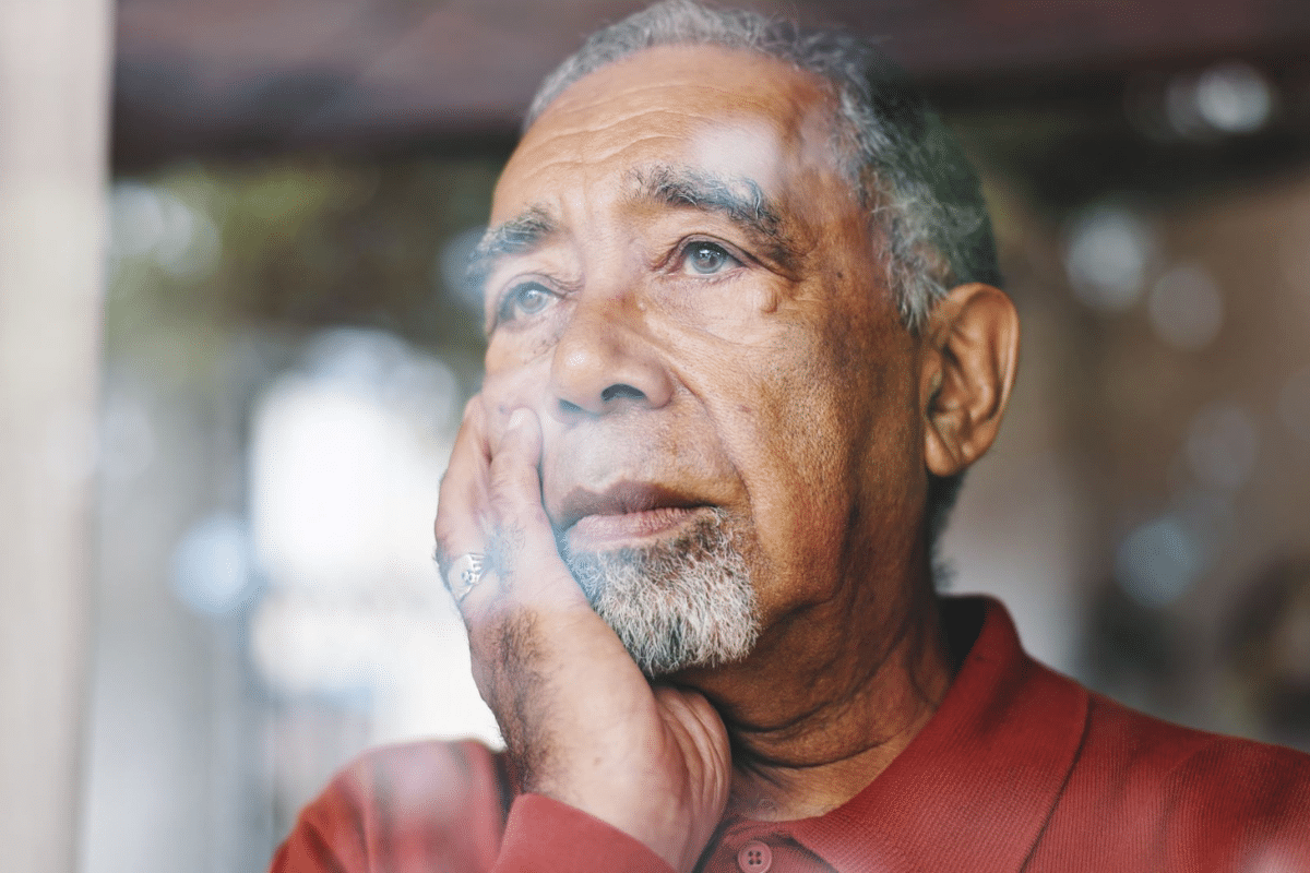older man looking out the window, worried