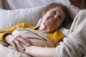 an older woman laying in bed next to her caregiver