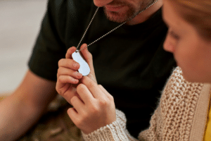 A woman holds the metal ID tag from the necklace around a man's neck