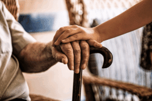 a young child rests their hand on their grandparent's hand