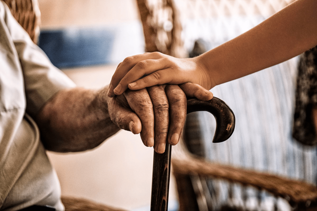 a young child rests their hand on their grandparent's hand