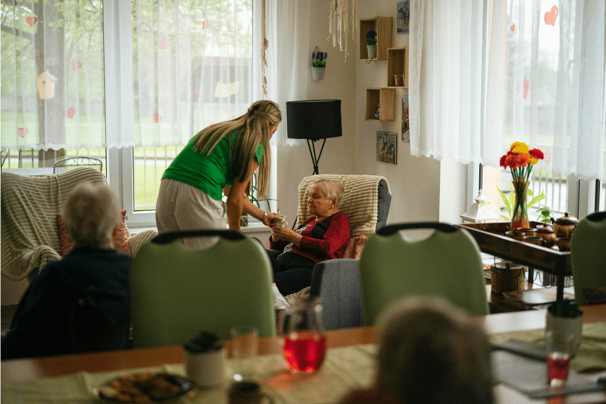 nurse helping older adult in nursing home common area