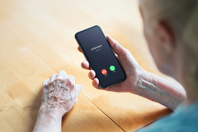 older adult looking at a spam call on their cellphone