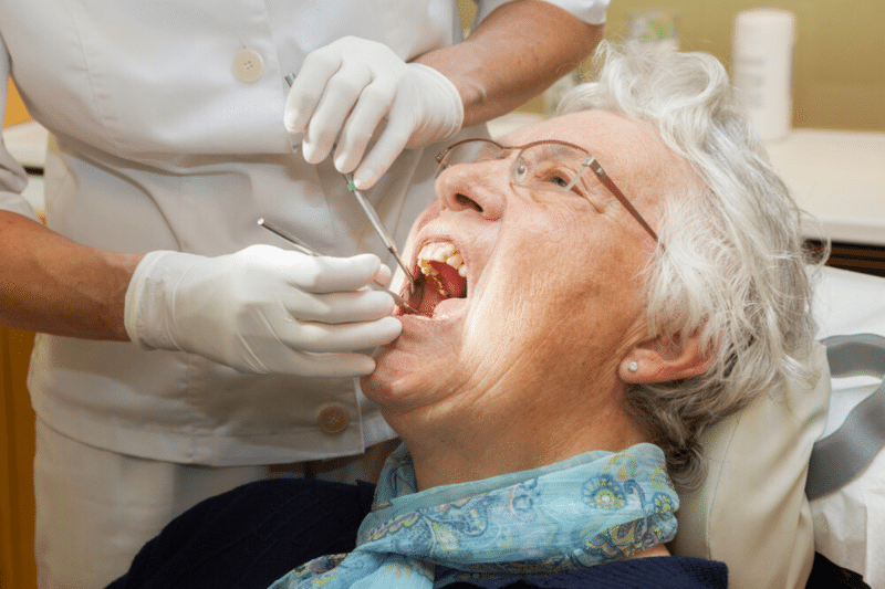 older adult at the dentist receiving a cleaning