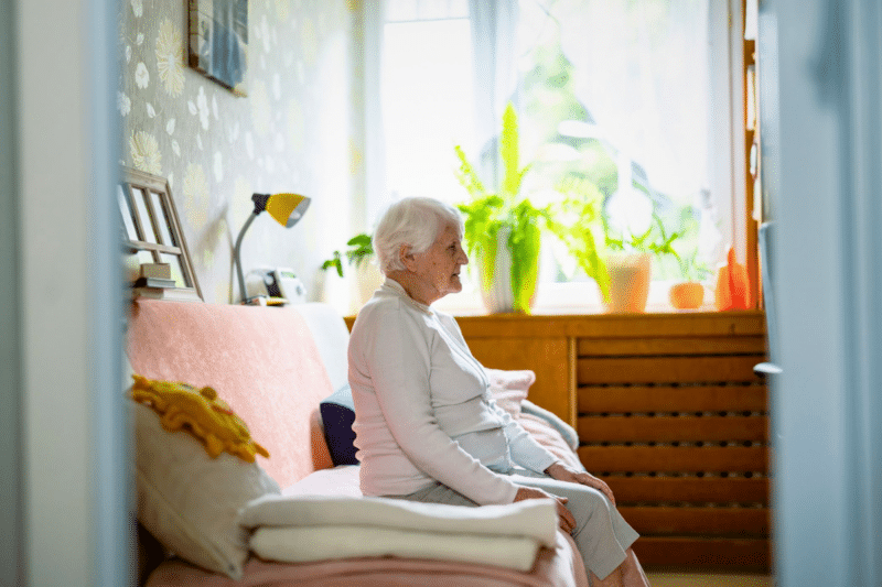 an older woman sitting on the edge of her couch
