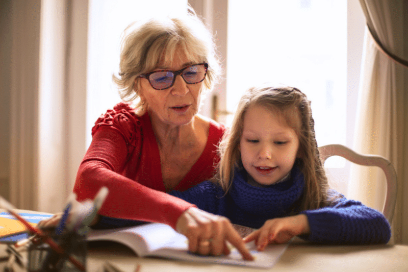 grandma reading with her grandchild at the table