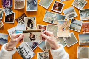 Two hands holding a photo above a bunch of photos scattered across a table