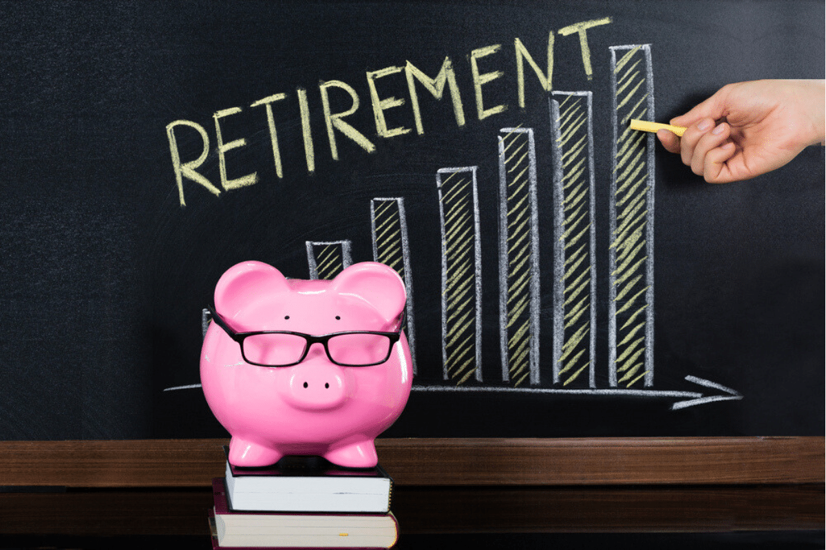 Retirement written in chalk on a blackboard with a pink piggy bank wearing glasses