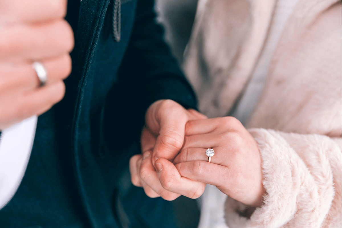 a couple wearing wedding rings hold hands
