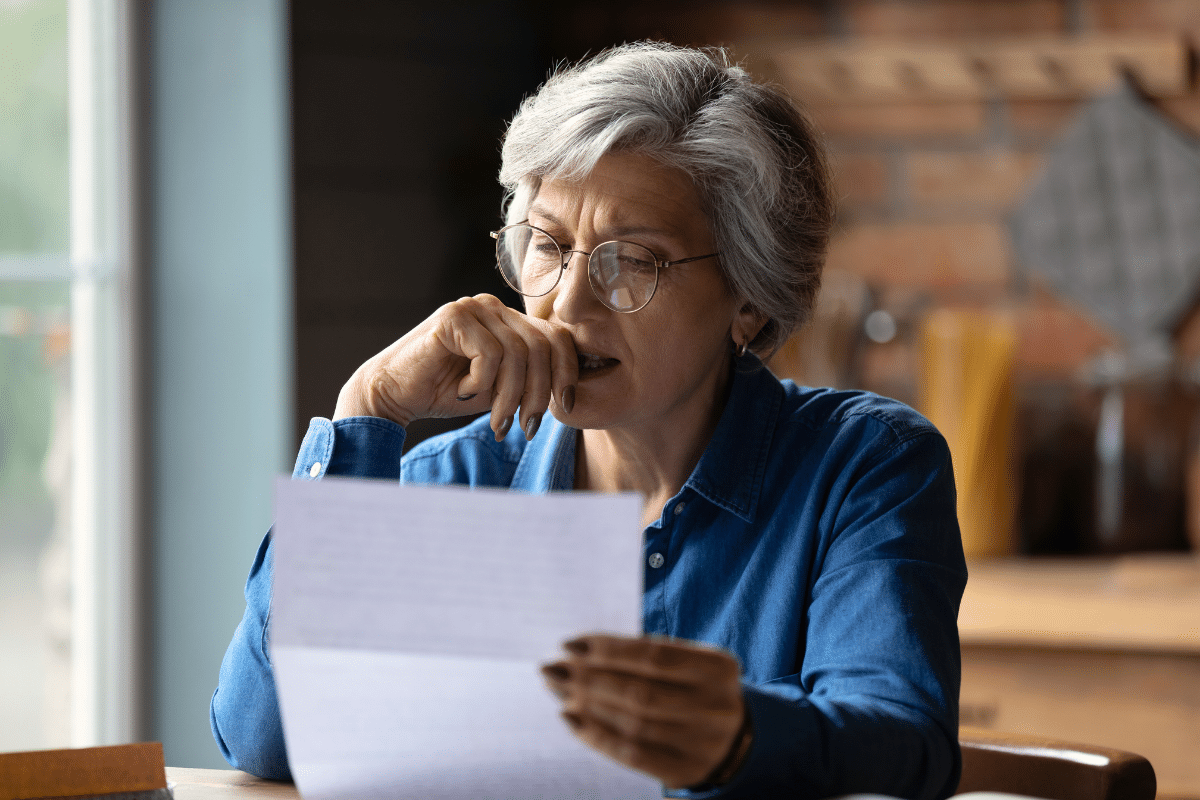 Older adult woman reading a paper nervously.