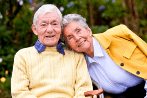 Elderly couple sit on a bench wearing shades of blue and yellow