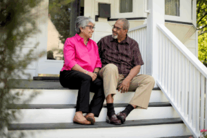 a happy older couple sitting on steps of front porch
