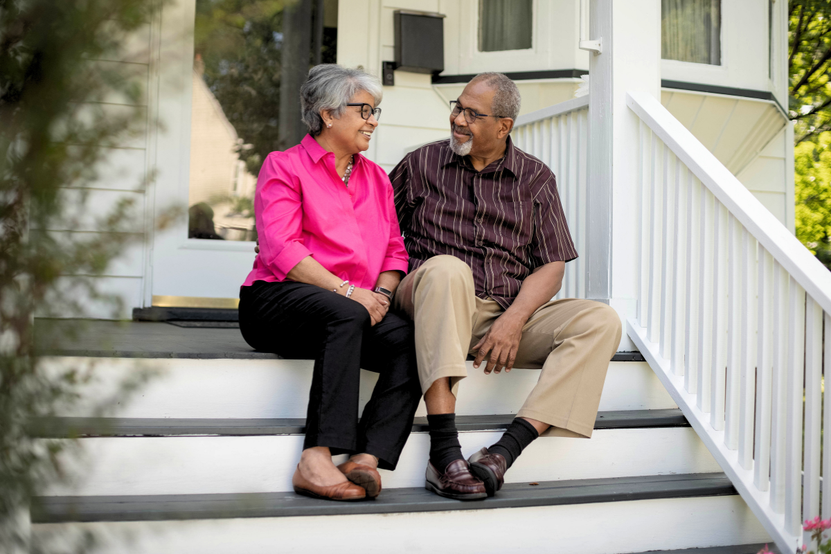 a happy older couple sitting on steps of front porch