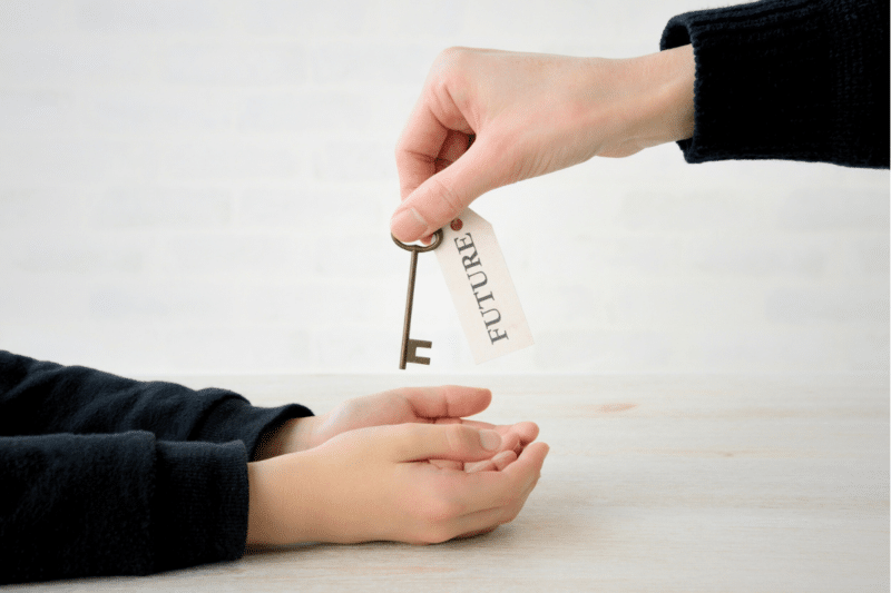 an adult handing a child a key with the word "future" on the tag