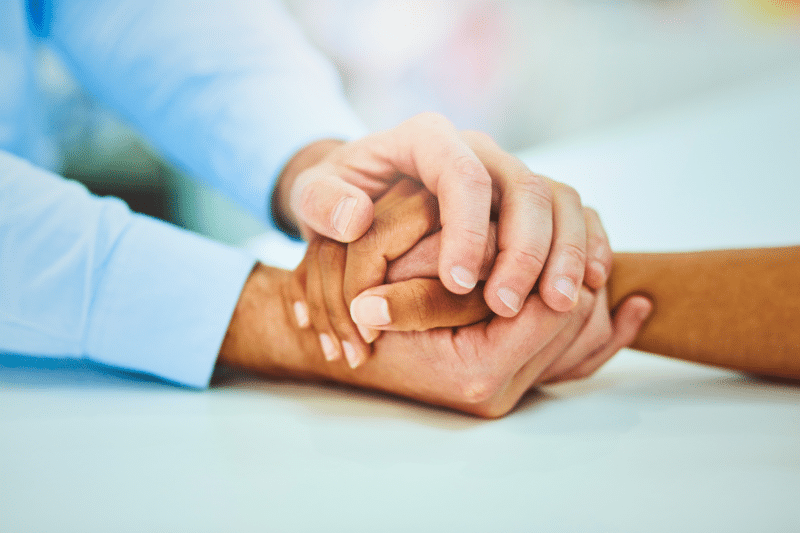 a set of hands consoling another set of hands