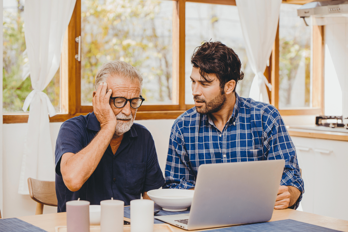 Adult sitting next to older father who is struggling with Alzheimer's